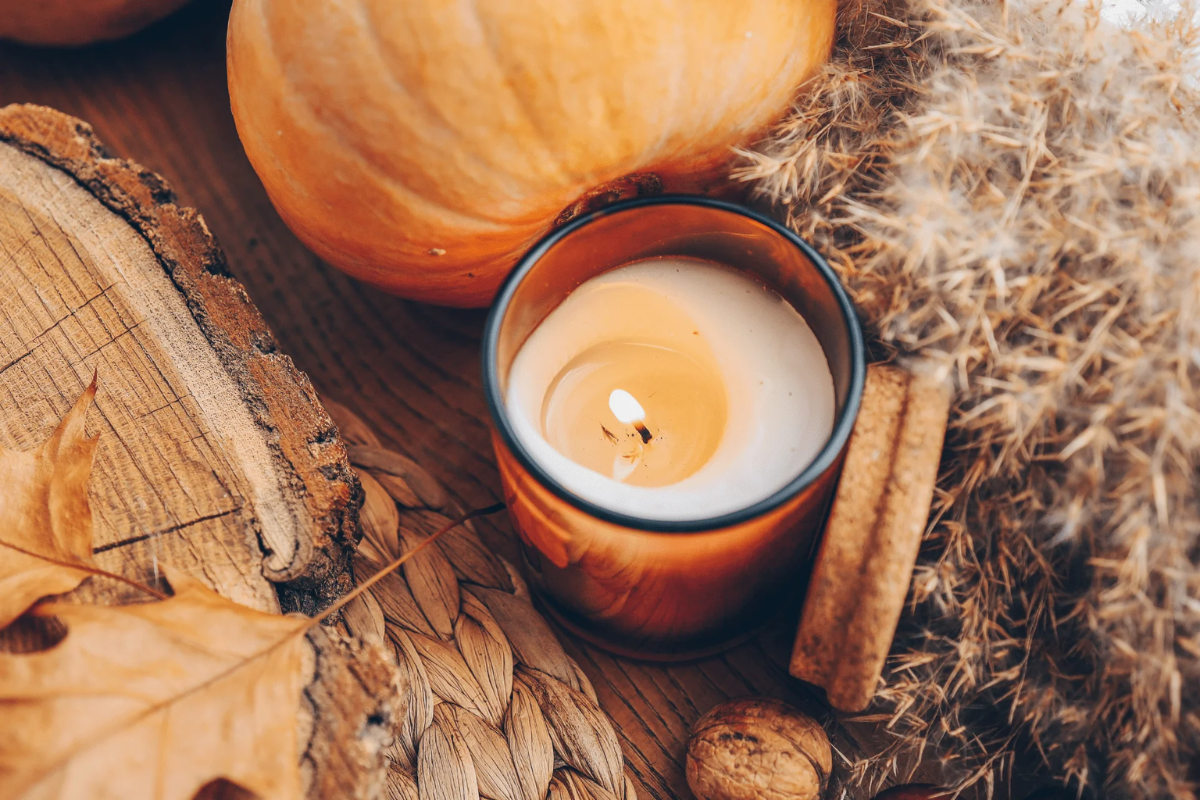 Candle showing severe wax tunneling with autumn elements on a wooden surface