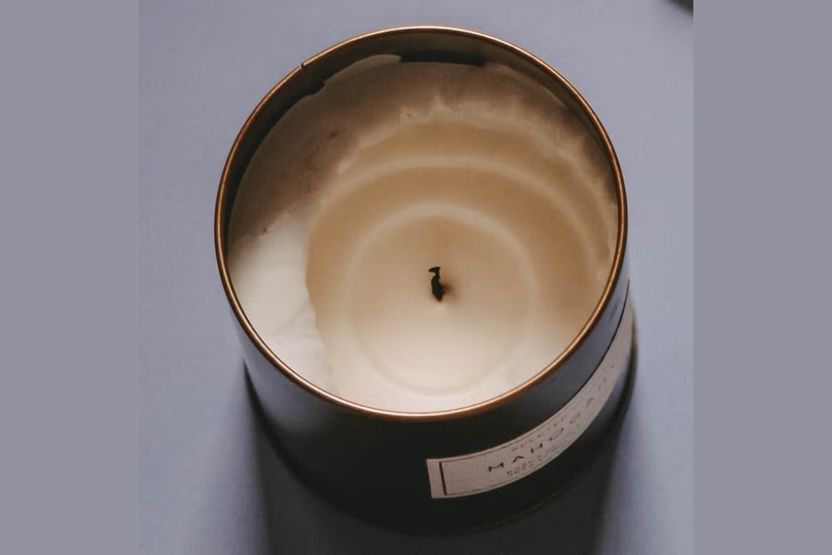 Candle showing severe wax tunneling in a metal container on a gray background