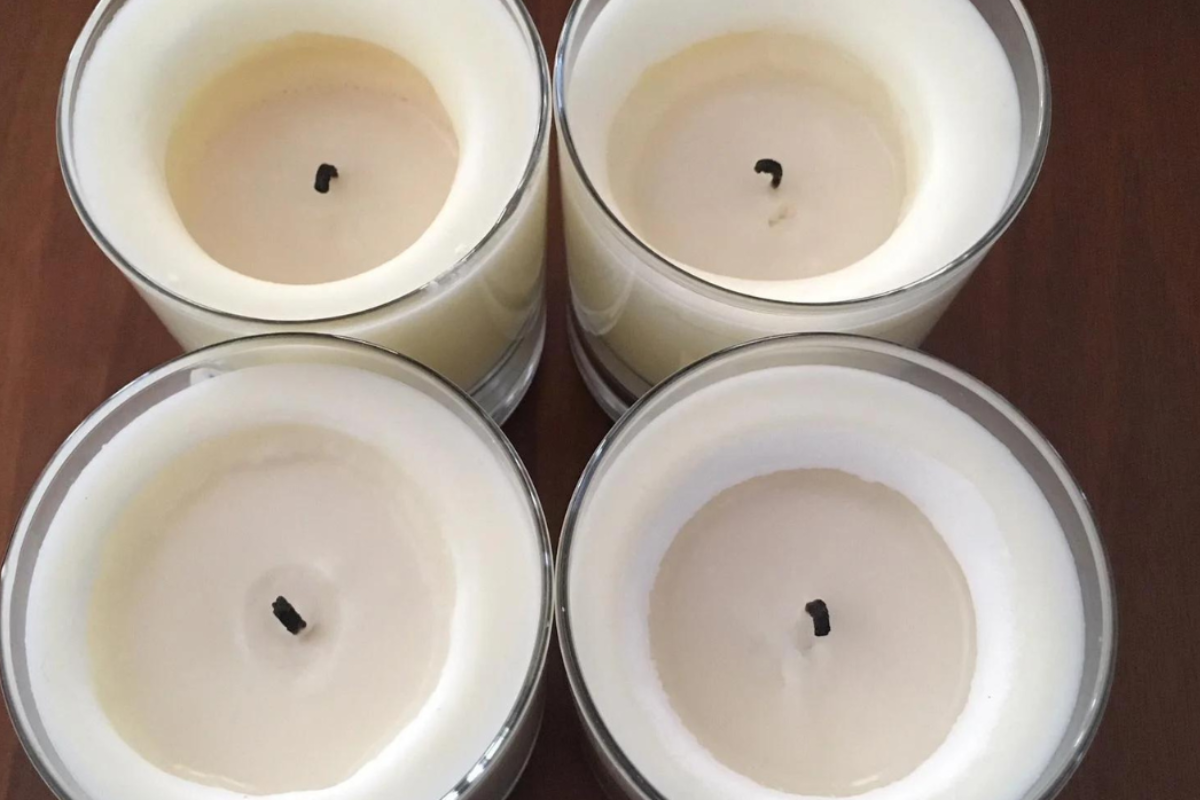 Four white candles that show wax tunneling where the candle has not burned all the way to the edge