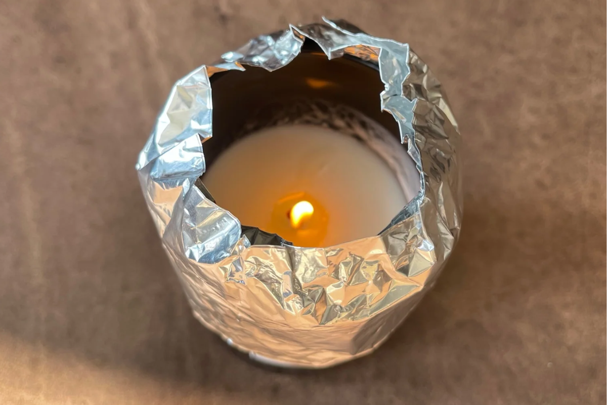 Candle surrounded by tin foil showing the tin foil hack to avoid wax tunneling in candles